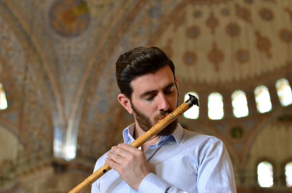 pexels-photo-415627-415627 A man in dress shirt plays flute under an ornate dome, capturing indoor musical expression.